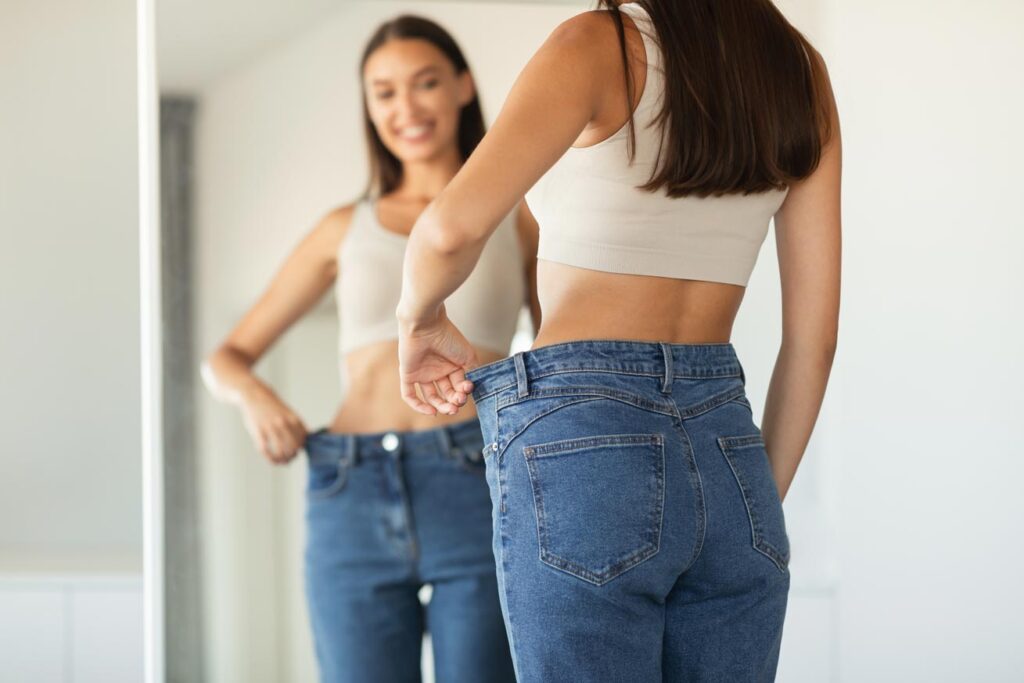 Kobieta wie jak schudnąć i przegląda się w lustrze widząc efekty odchudzania.